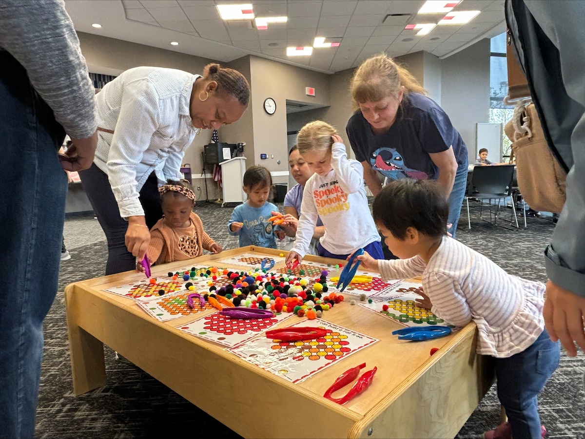 Toddlers and caregivers exploring colorful sensory tools during a play session at Sterling Heights Public Library — one of the best libraries in Macomb County for interactive early childhood development activities.
