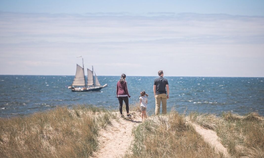 Family enjoying a sunny day on the beach in Saugatuck, Michigan — one of the best things to do with kids in the area.