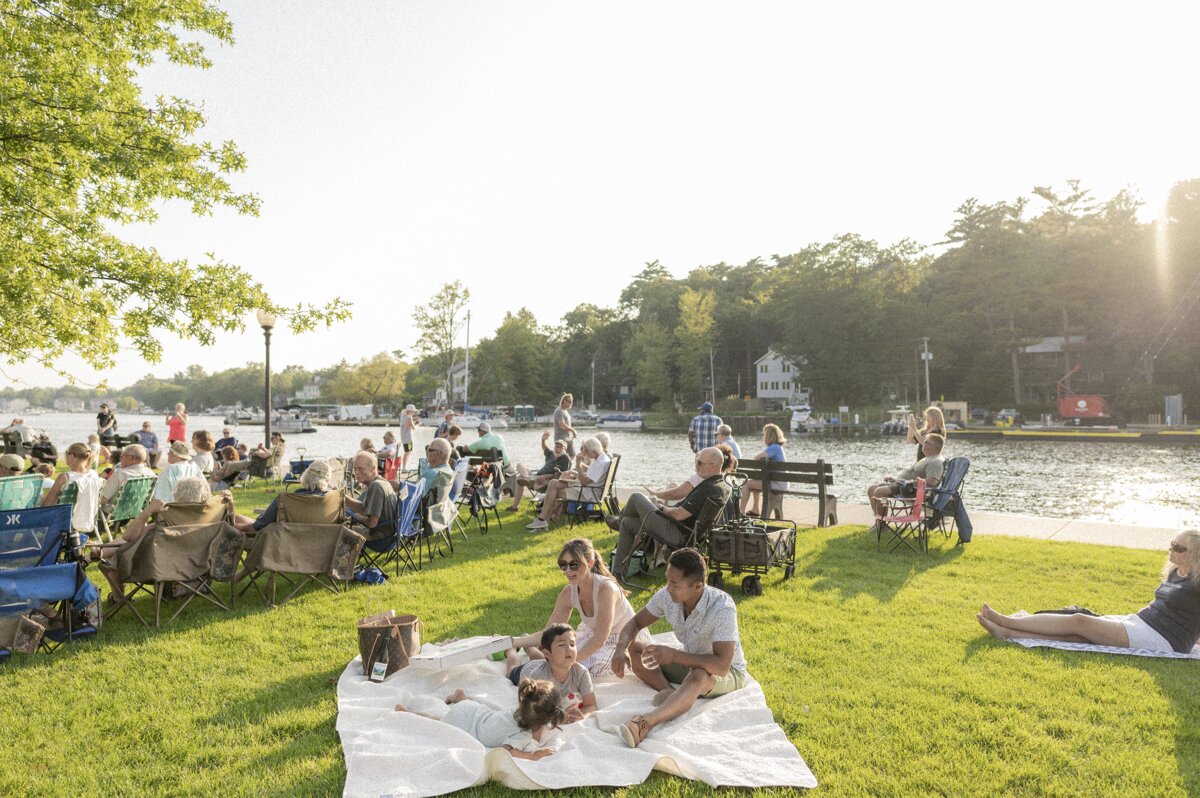 Families enjoying a sunny picnic and waterfront concert along the Kalamazoo River, one of the best things to do in Saugatuck Michigan with kids.