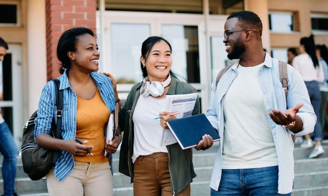 College students walking and talking on campus, representing those impacted by block tuition in Michigan as universities adopt new flat-rate tuition models.