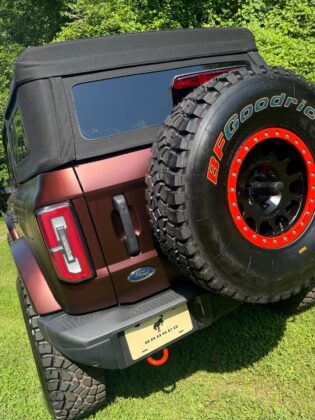 Rear view of a red Ford Bronco with BFGoodrich off-road spare tire and Bronco branding, showcased at Bronco Wild Fund Days outdoor event.