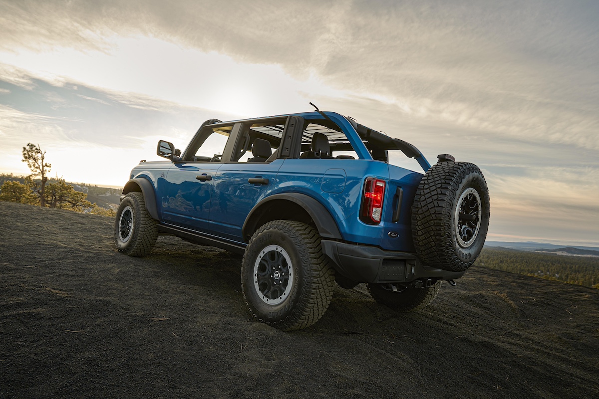 Blue Ford Bronco parked on a scenic mountaintop at sunset, showcasing a perfect setting for family fun and off-road adventures.