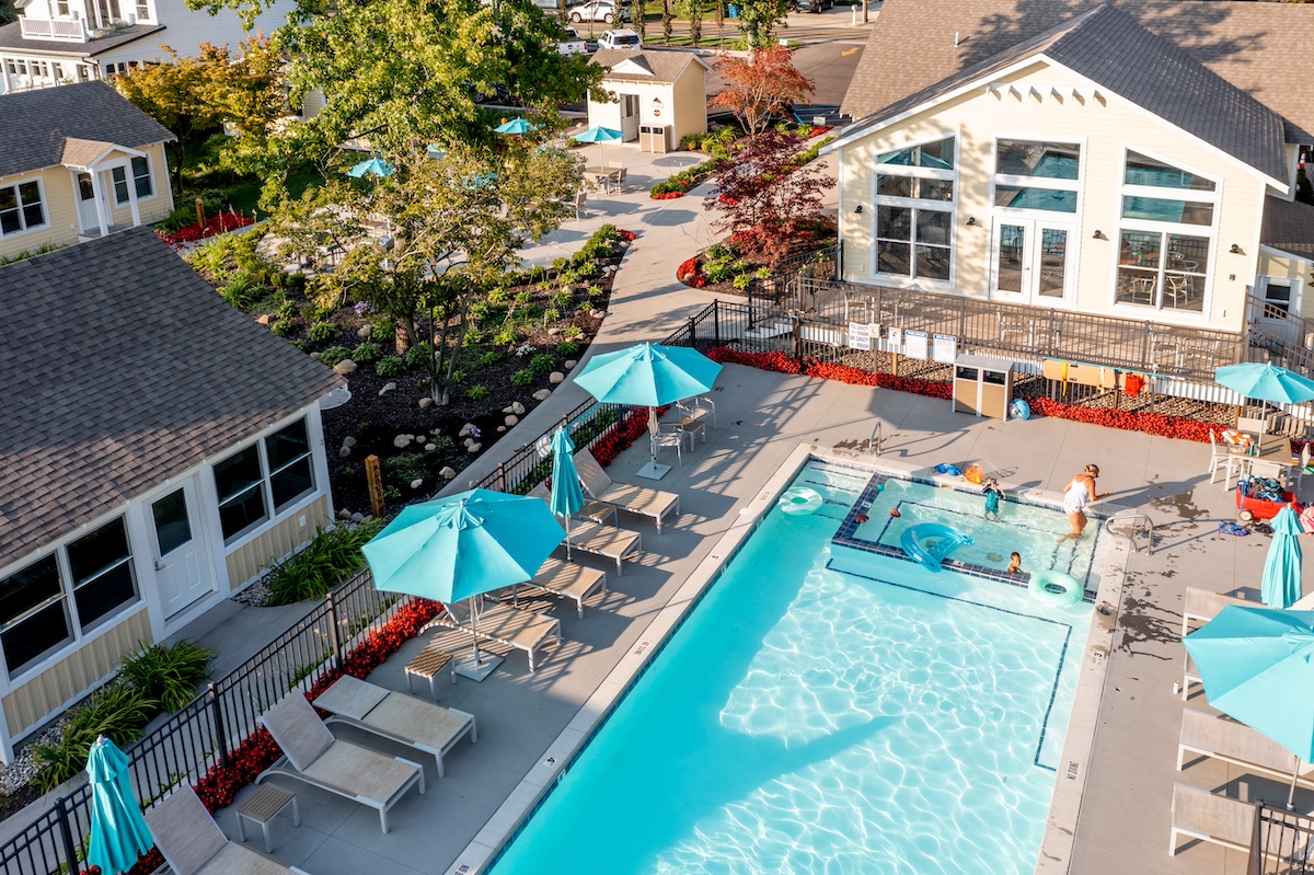 Aerial view of Old Pike Cottages, one of the top family hotels in Saugatuck Michigan, featuring a clean pool area, shaded lounge chairs, and family-friendly amenities.