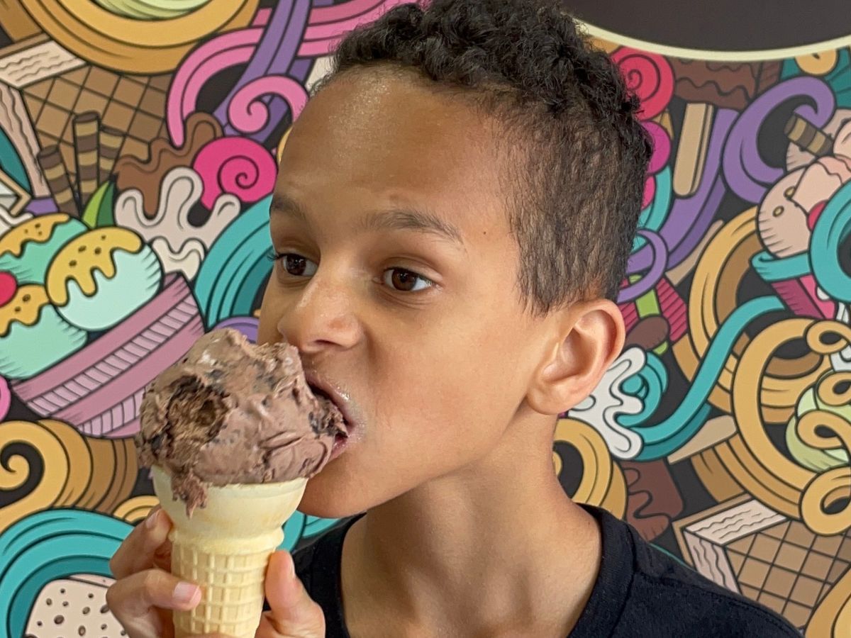 Child eating Michigan Pot Hole ice cream cone with chocolate chunks at a local scoop shop in Michigan