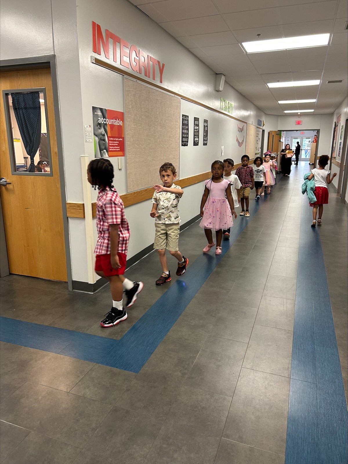 Young students at Quest Charter Academy walk in a line through the school hallway, highlighting strong attendance and classroom readiness.