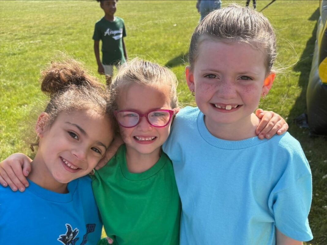 Three smiling students pose together outdoors at Quest Charter Academy, promoting positive attendance and school engagement.