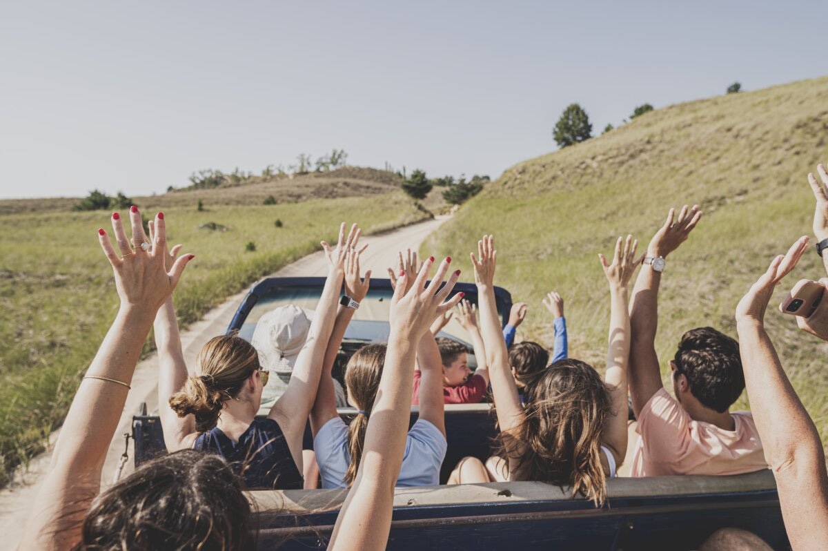 Group of people raising their hands on a thrilling dune ride near Oval Beach at Saugatuck State Park, a must-visit Lake Michigan destination.