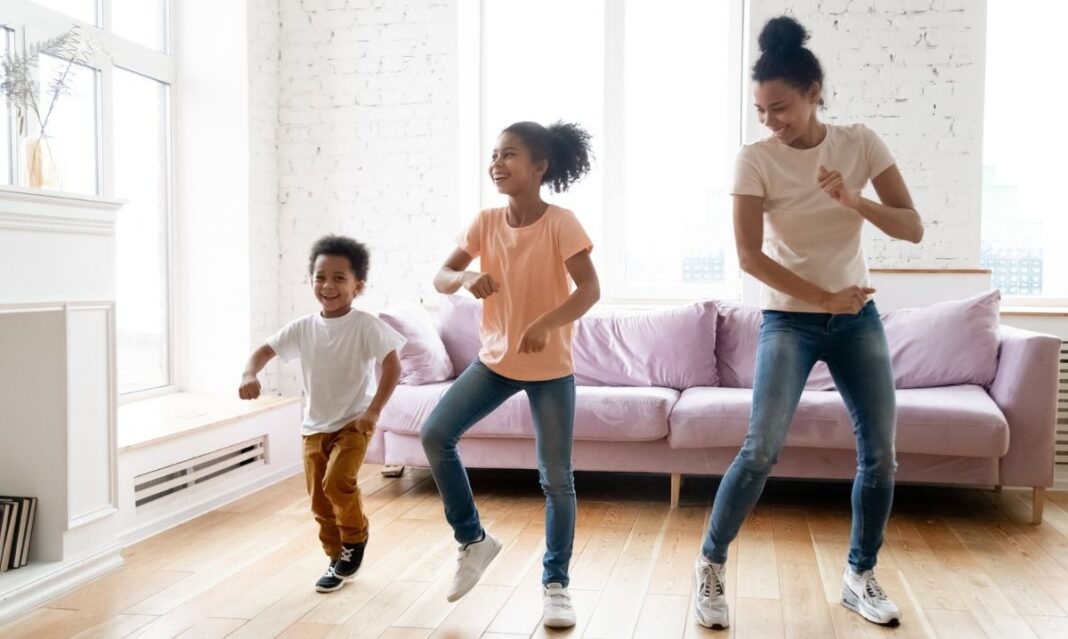 Mother and children dancing together in a living room, showing a fun exercise snack activity for kids with autism.