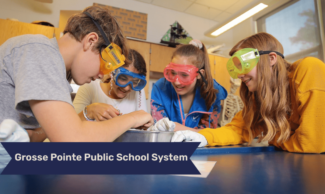 Four students wearing safety goggles and gloves gather around a lab table, closely examining a project or experiment together in a science classroom.