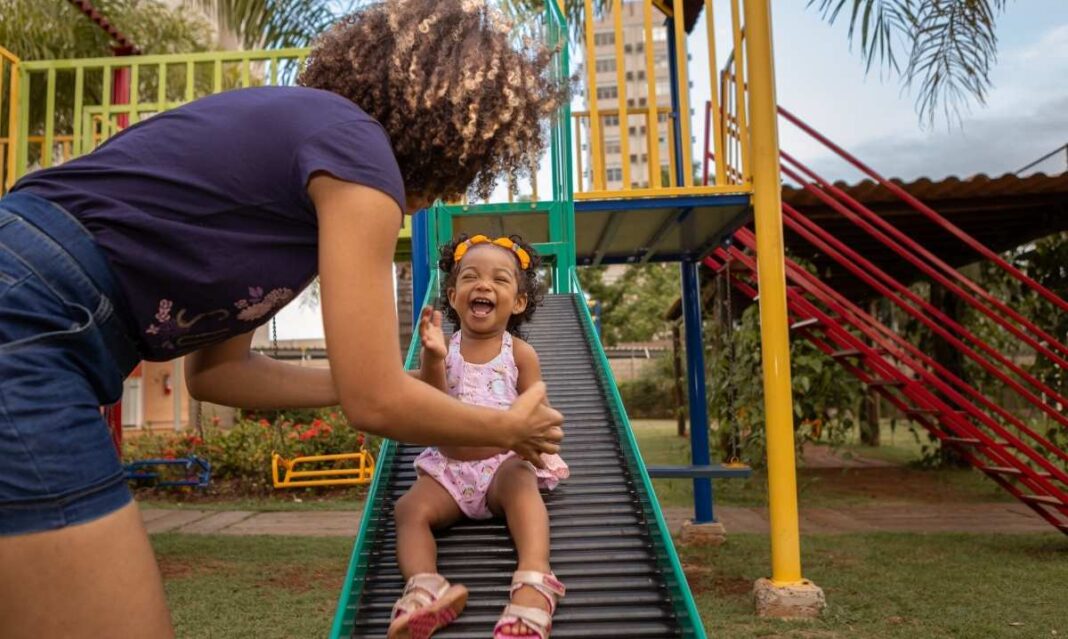 Chicagoland weekend things to do with kids: mom catching a laughing toddler on a playground slide, a joyful family moment for local outings.