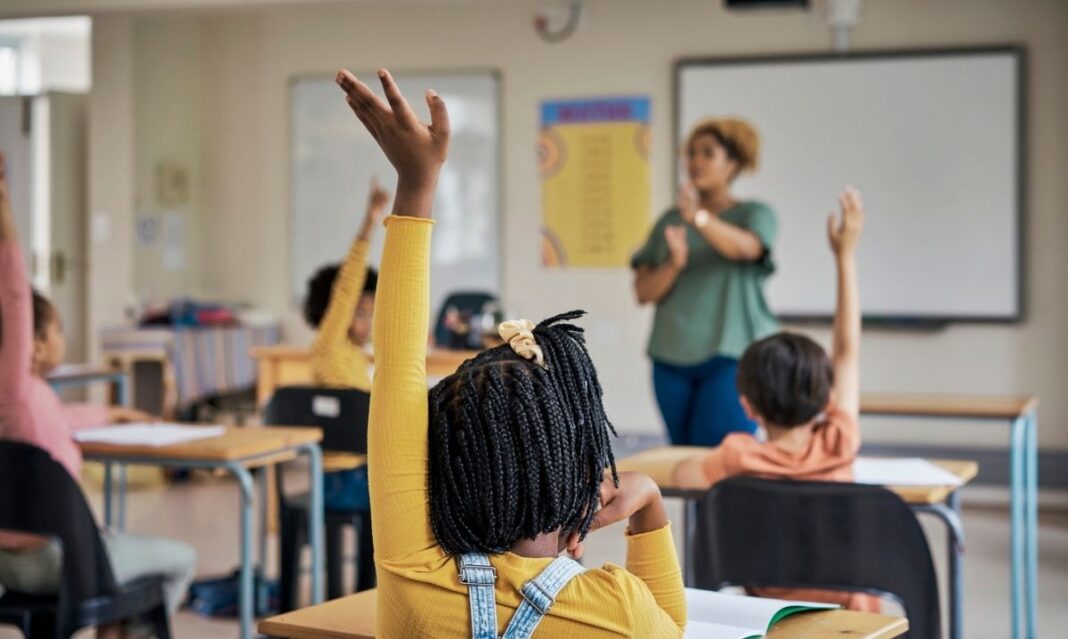Students raising hands in a classroom as a teacher leads discussion, representing Detroit Public Schools special education changes in 2025.