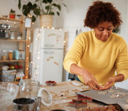 Parent bakes Christmas cookies at home with dough and cutters on the table for an easy holiday recipe kids can help make.