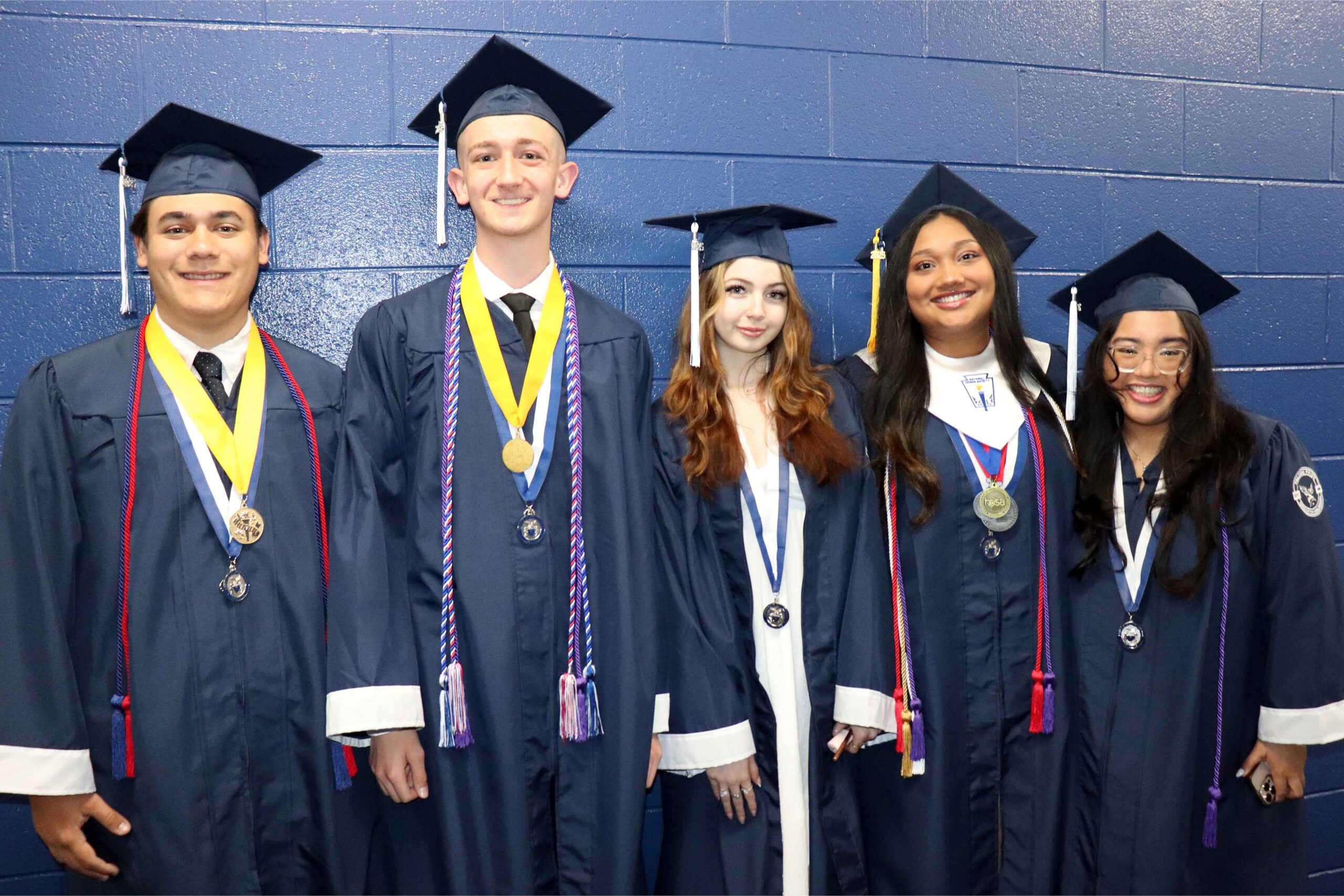 Farmington Public Schools high school graduates smile in caps and gowns, celebrating academic achievement and the end of their K-12 journey.