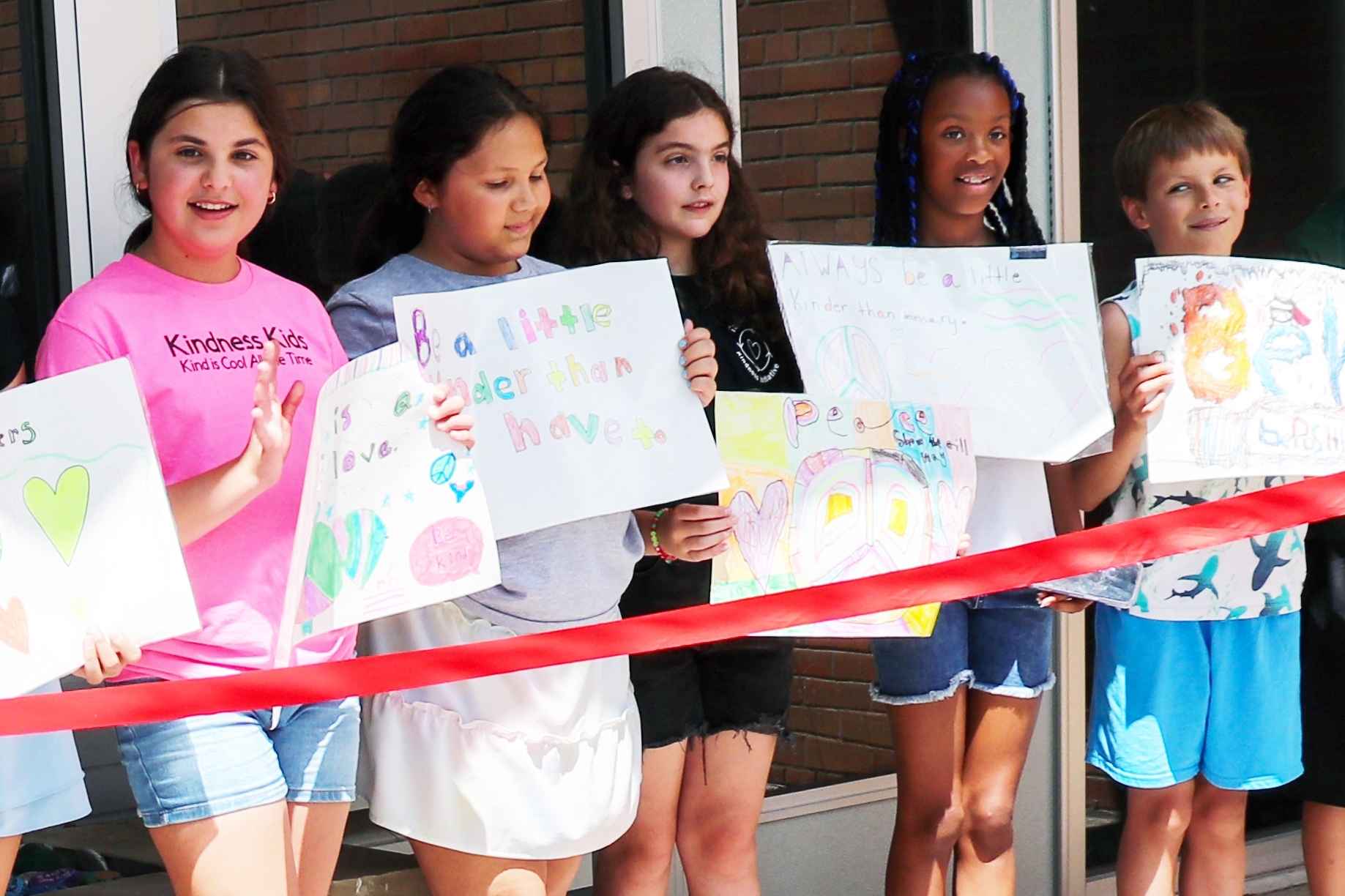 Farmington Public Schools students hold handmade kindness and peace posters during a school event, highlighting community and creativity.