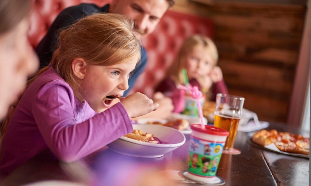 A young girl enjoys a meal with her family at Lansing Brewing Company with pizza, drinks and kid friendly dining options on the table.