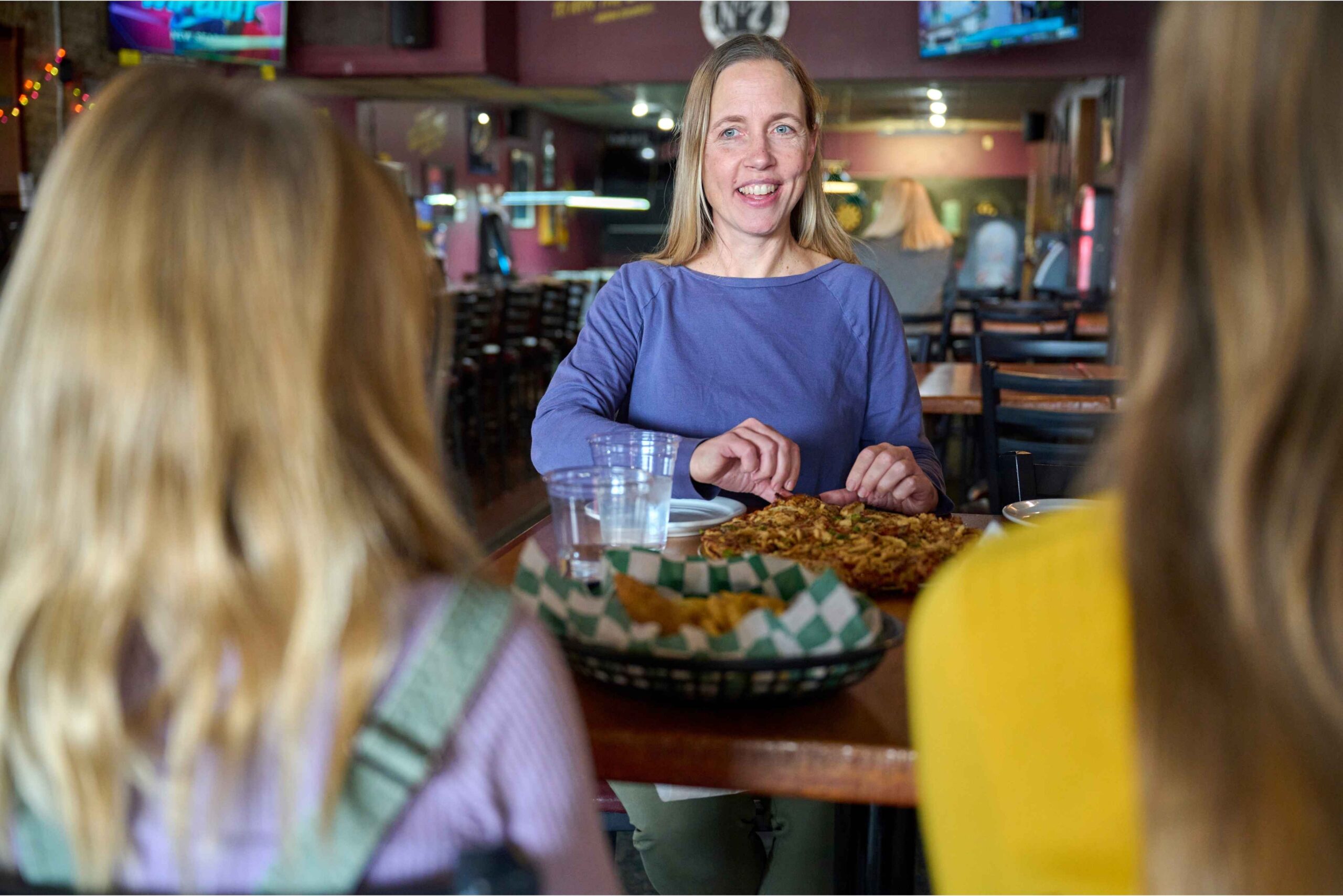 A mom smiles at her kids while sharing food at The Nut House in Lansing during a family meal inside the casual restaurant.