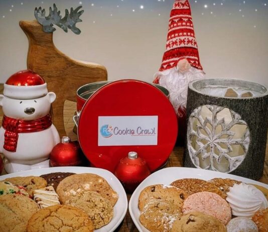 Plates of assorted holiday cookies with a red cookie crawl tin festive decorations and ornaments for the Royal Oak Cookie Crawl event
