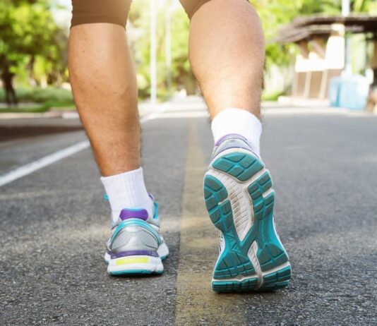 Close-up of a person walking in athletic shoes on a paved road, representing outdoor fitness, health walks, and community walk events.