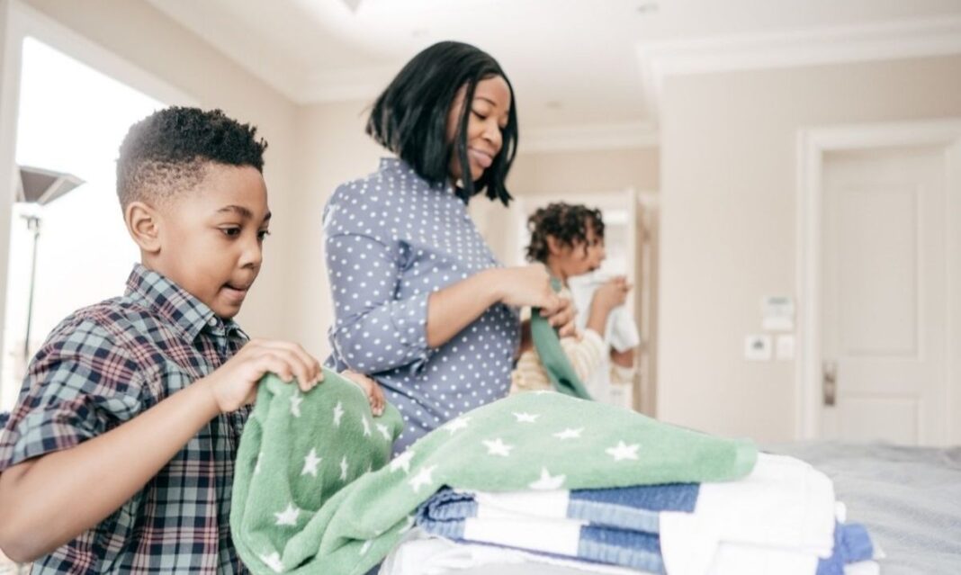 Parent and child folding laundry together at home as part of everyday learning for autism and building therapy balance through daily routines.