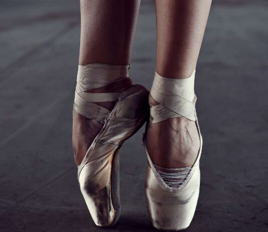 Las Posadas celebration at Henry Ford Museum Close-up of ballet dancer's feet in worn pointe shoes poised on tips, highlighting dance performance for Las Posadas celebration event.