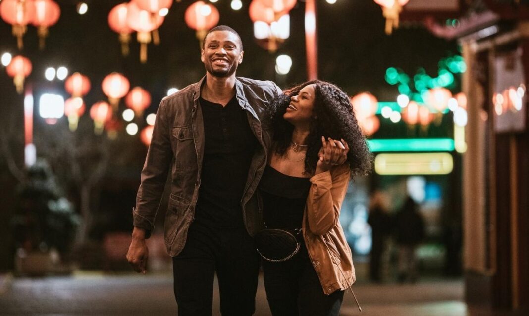 Couple walks together at night under lantern lights in downtown Detroit during an affordable $50 date night for parents.