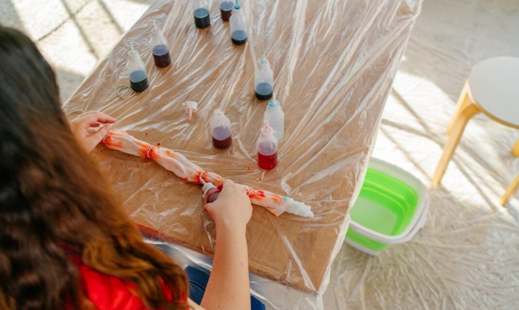 Child applying colorful dye to fabric during a family tie-dye class at Detroit Dye House, representing hands-on art workshops for kids and parents.