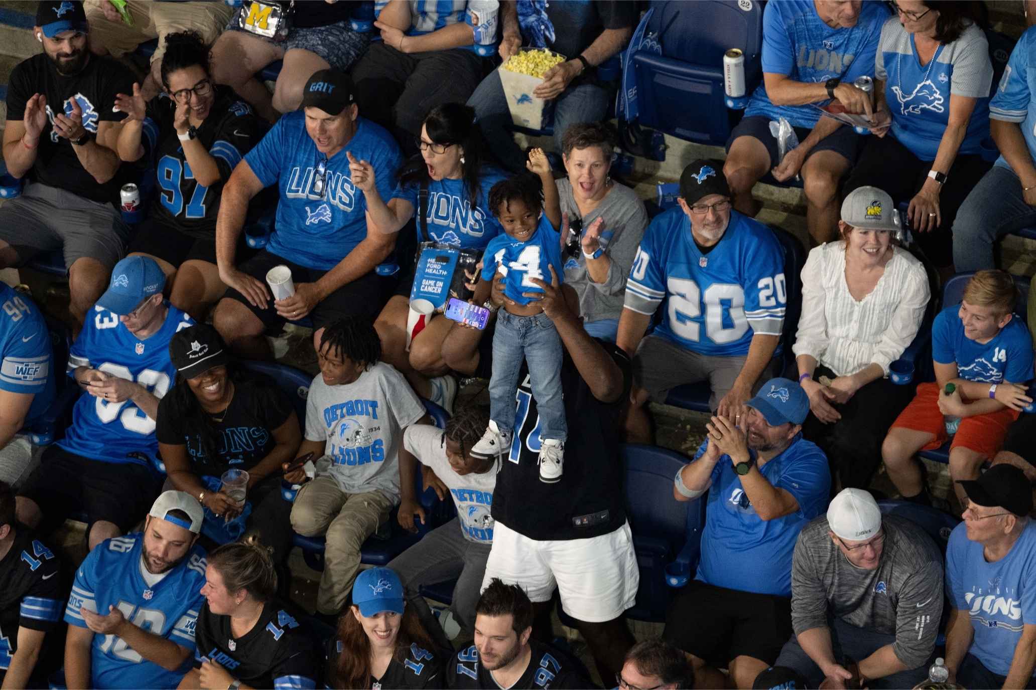 Detroit Lions fans cheer in the stands at Ford Field during a family-friendly football game, showcasing Michigan’s vibrant football culture.