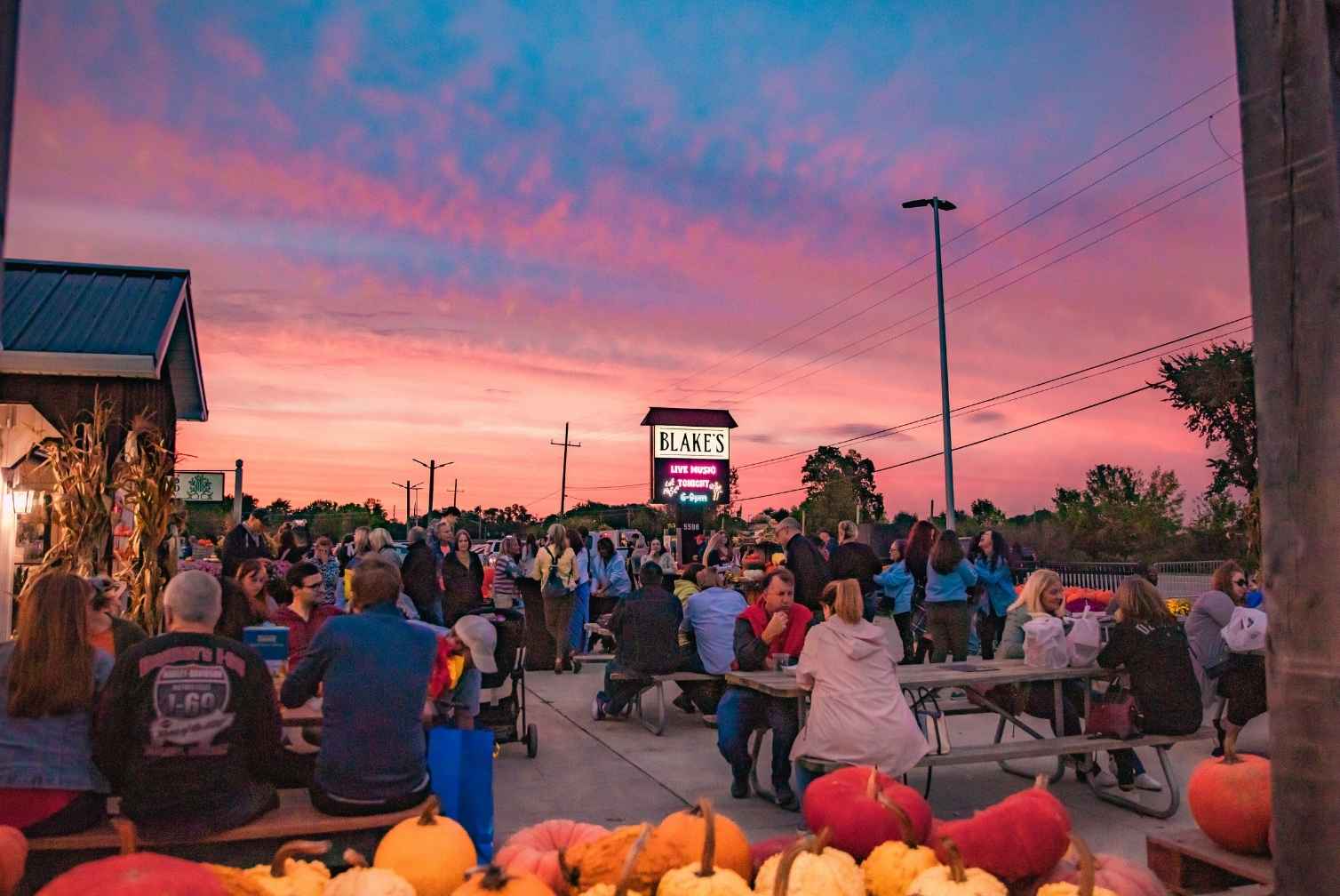 Families sit under a colorful sunset at Blake’s Big Apple in metro Detroit during the fall haunted attractions season.