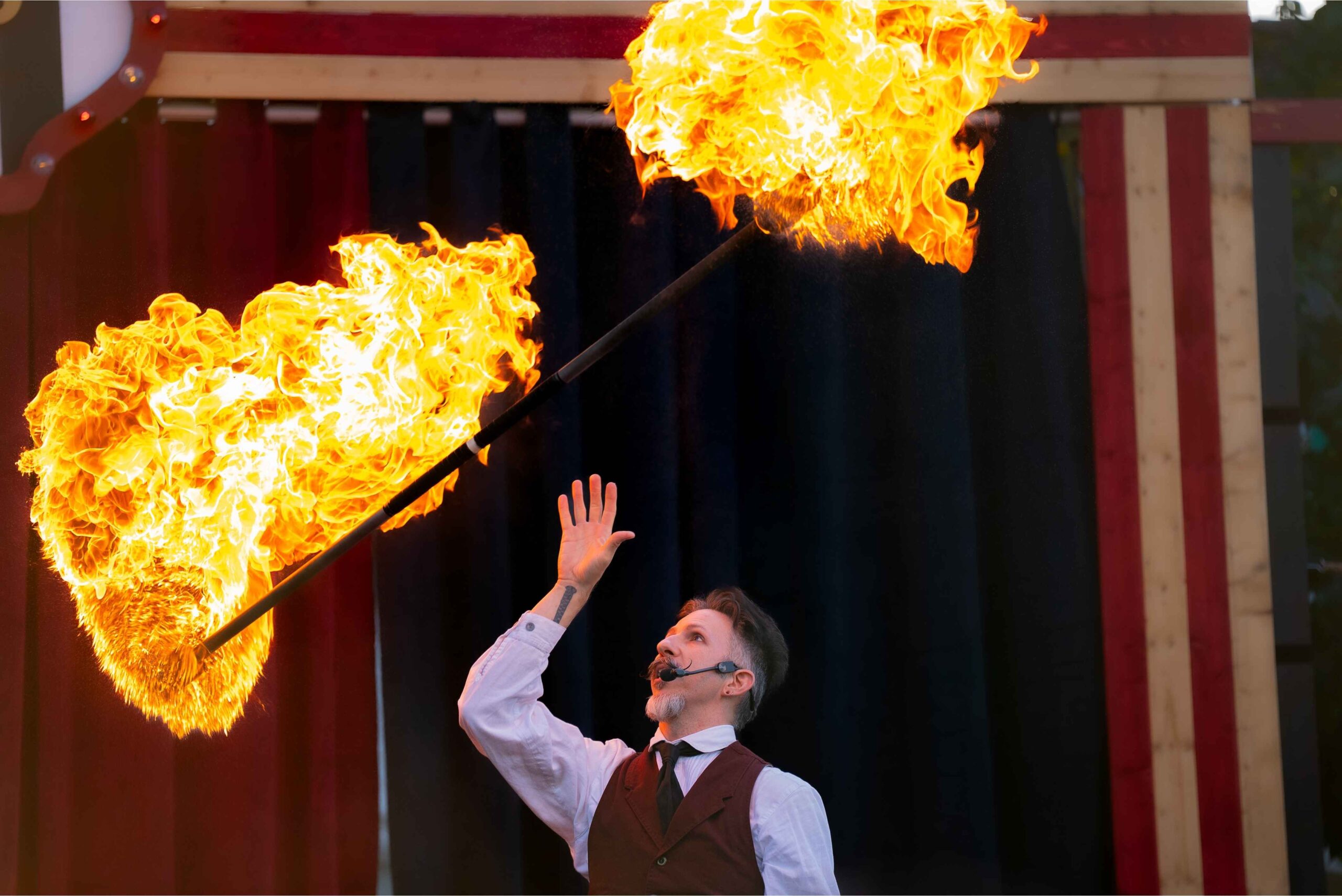 A performer balances a flaming torch during a live Halloween show at Greenfield Village, entertaining families with fire tricks.