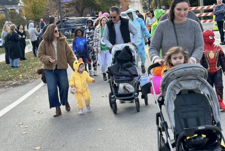 Families and kids in costumes take part in the Franklinstein Frenzy Halloween parade in downtown Franklin with strollers and trick-or-treat bags.