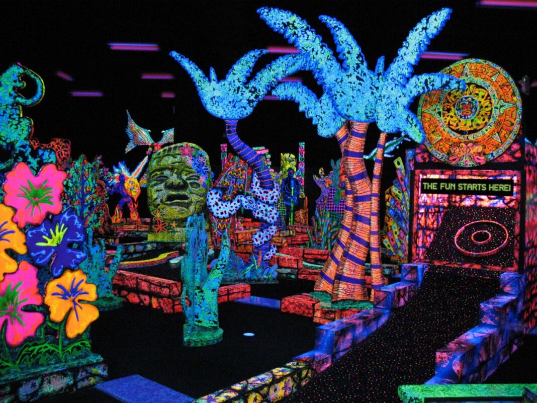 Glow-in-the-dark mini golf course at Putting Edge in southeast Michigan with neon palm trees, murals, and bright family fun decor.