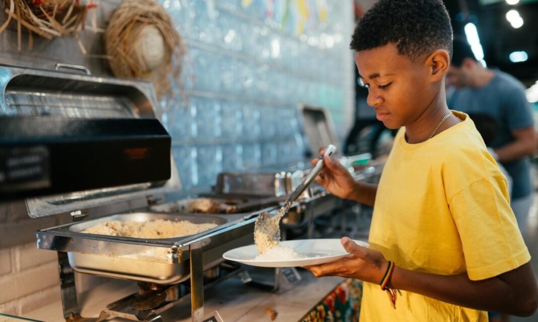 Child serving food at a buffet restaurant in metro Detroit, representing family-friendly buffets like Golden Corral and Fuji Japanese Buffet.