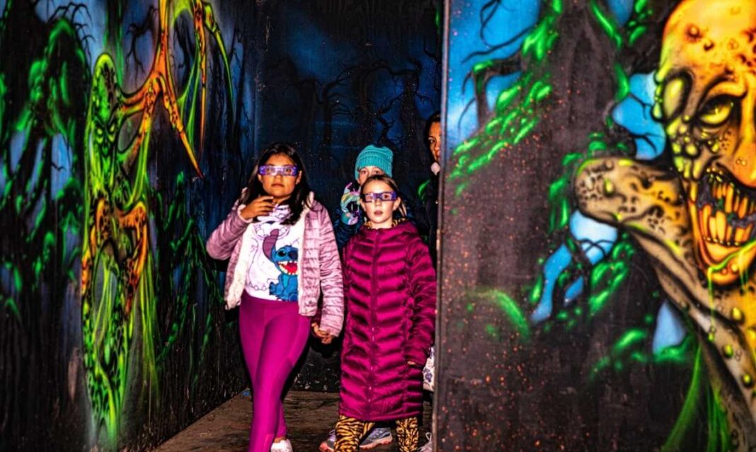 Kids wearing 3D glasses walk through the colorful Spookyland maze at Blake’s haunted attractions in metro Detroit.