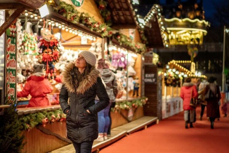 Visitors stroll through the festive Downtown Rochester Lagniappe event with holiday lights, local shops, and Christmas market displays.