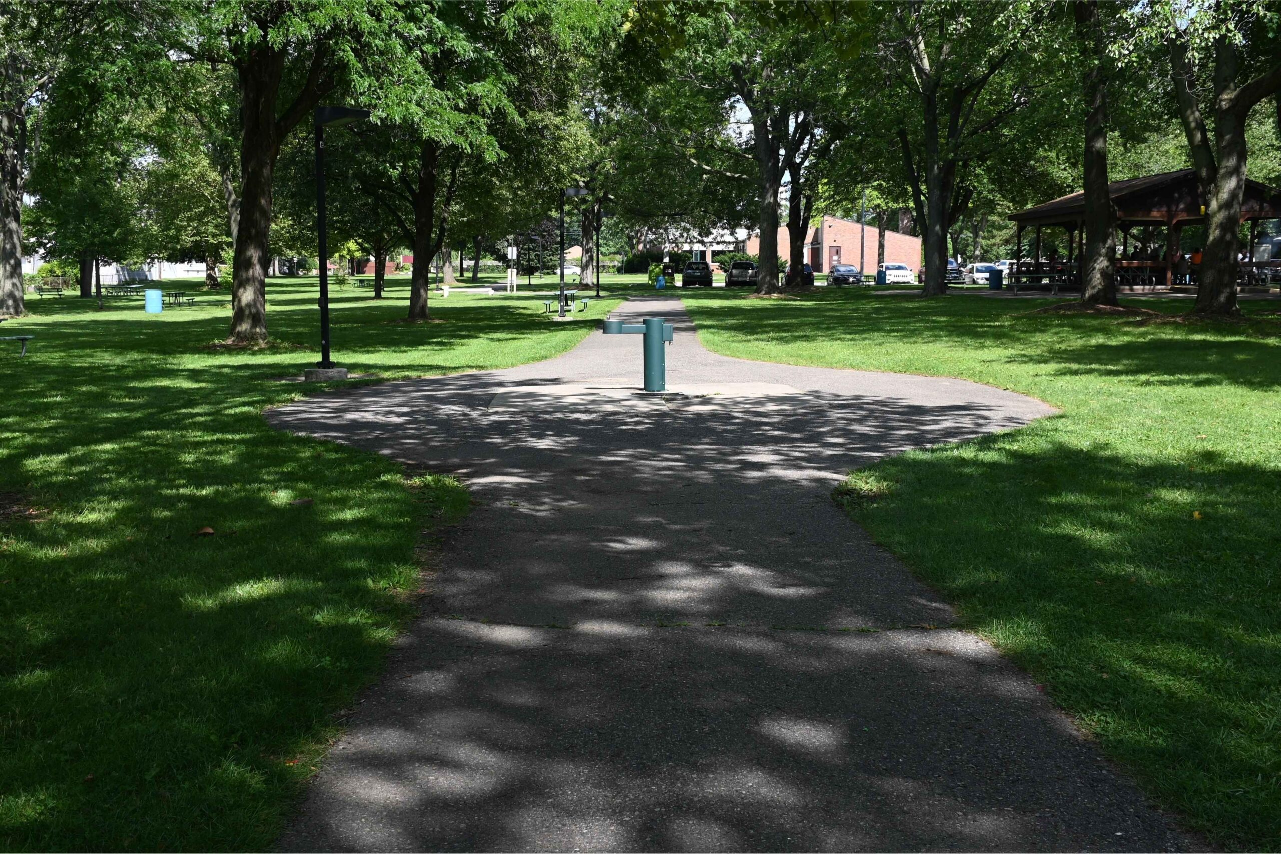 Pathway through Memorial Park in Center Line, Michigan, surrounded by trees, picnic areas and open green space for family recreation.