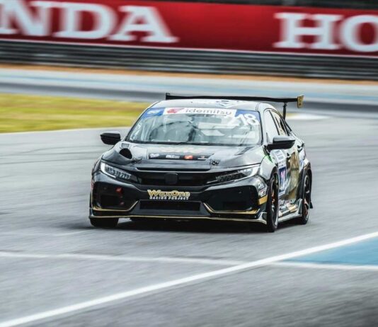 A black racecar speeds around a track, similar to the vehicles featured at Bartlett’s Kids Club NASCAR ARCA event in Canton Michigan.