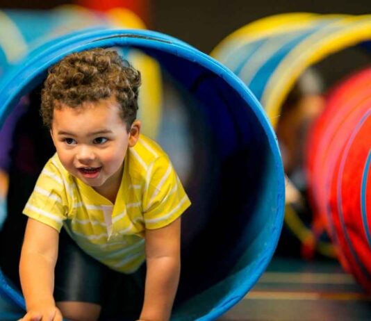 A young child crawls through a play tunnel during Open Play at Troy Gym TG4, enjoying active fun and movement in a safe setting.