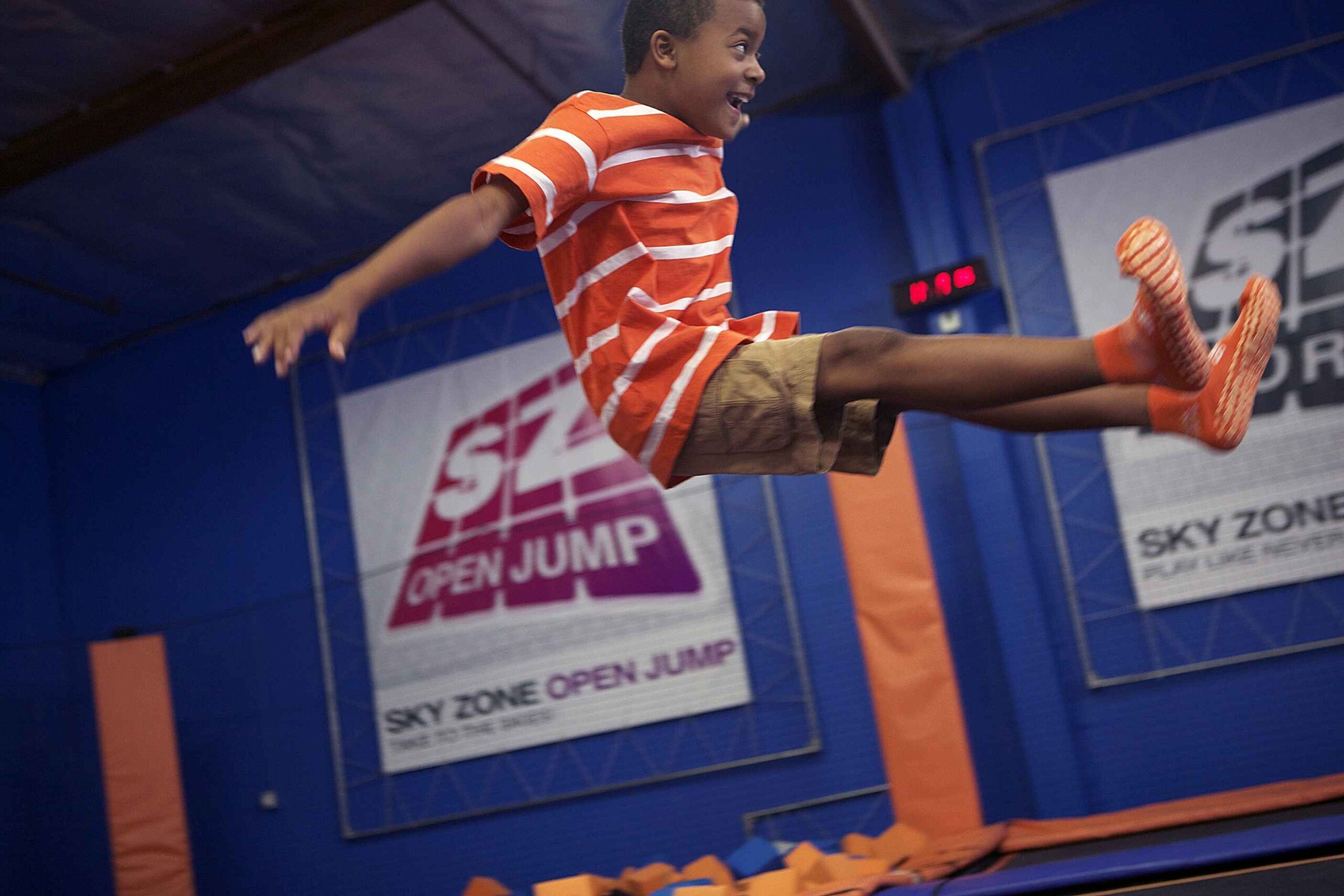 Excited boy jumps high at Sky Zone trampoline park in Michigan during indoor playtime full of fun and energy.