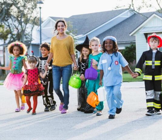 Kids in Halloween costumes trick-or-treating with a parent during the Trick or Treat Halloween Stroll in Canton Michigan neighborhood.