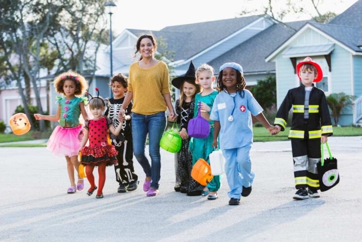 Kids in Halloween costumes trick-or-treating with a parent during the Trick or Treat Halloween Stroll in Canton Michigan neighborhood.