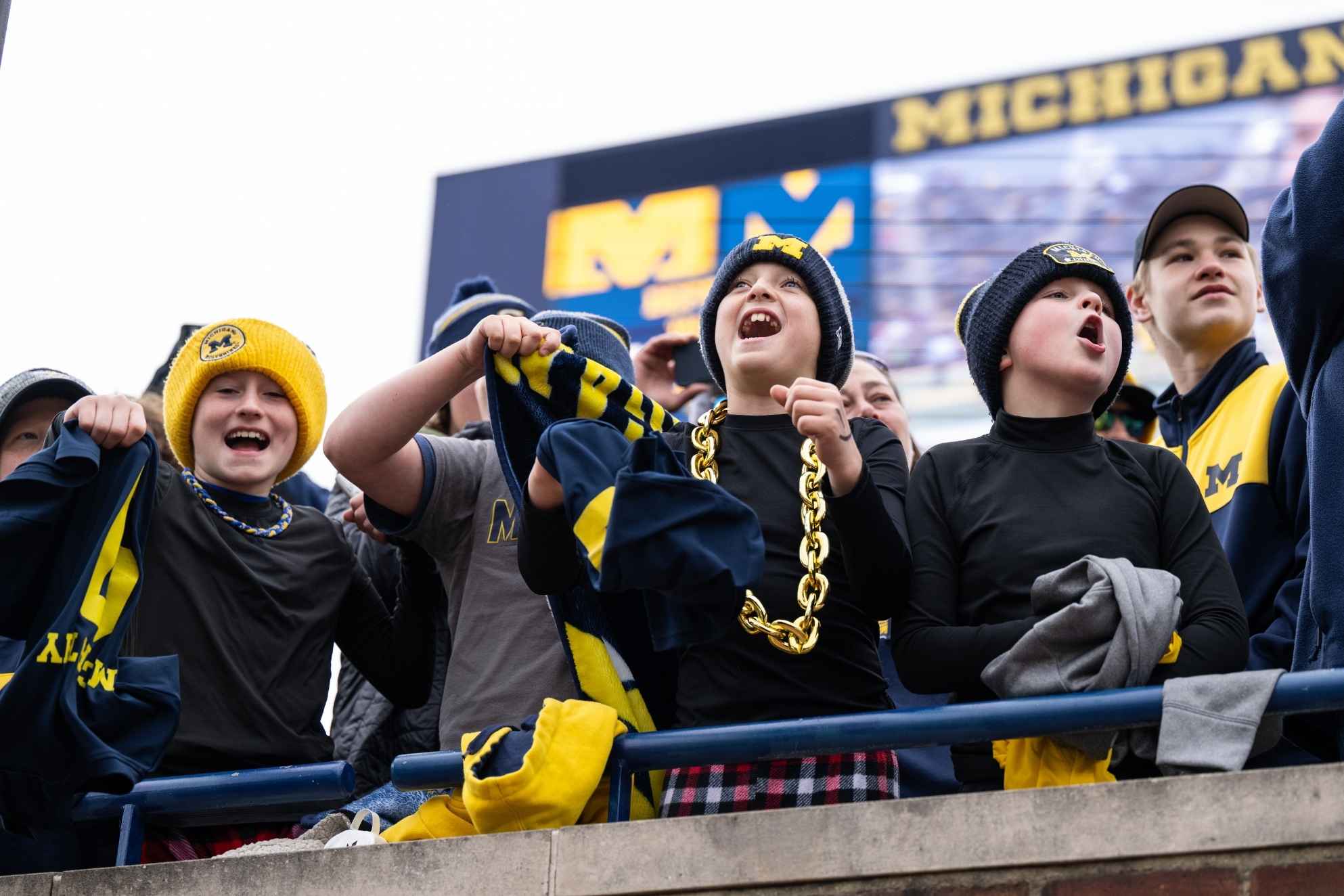 University of Michigan fans cheer with their families at a Wolverines football game, showing the excitement of Michigan’s fall football season.