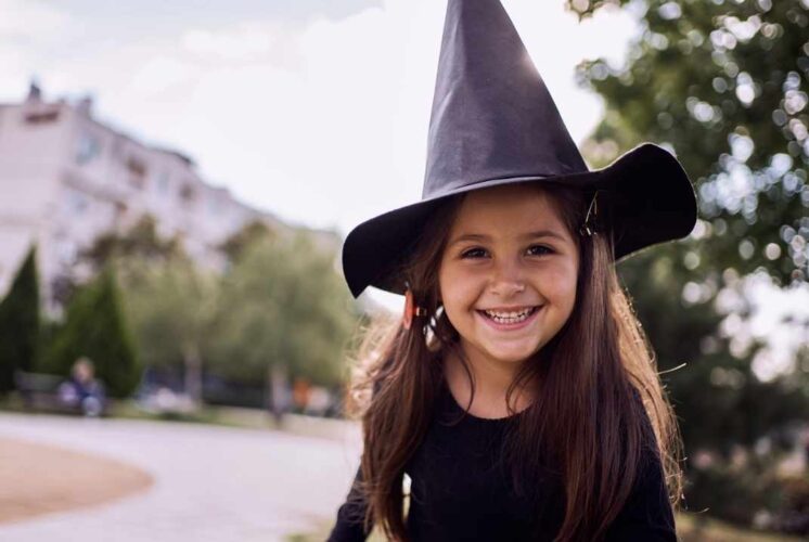 A smiling child in a witch hat enjoys Winter at Hogwarts at Howell Nature Center, a magical event with owls, potions and crafts.