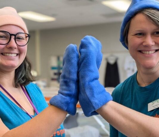 Makers smiling in fleece hats and mittens during the Crafted in Kindness event at The Hawk Makerspace where kids 12 and up can learn to sew
