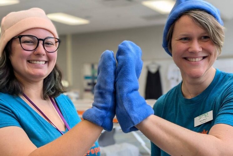 Makers smiling in fleece hats and mittens during the Crafted in Kindness event at The Hawk Makerspace where kids 12 and up can learn to sew