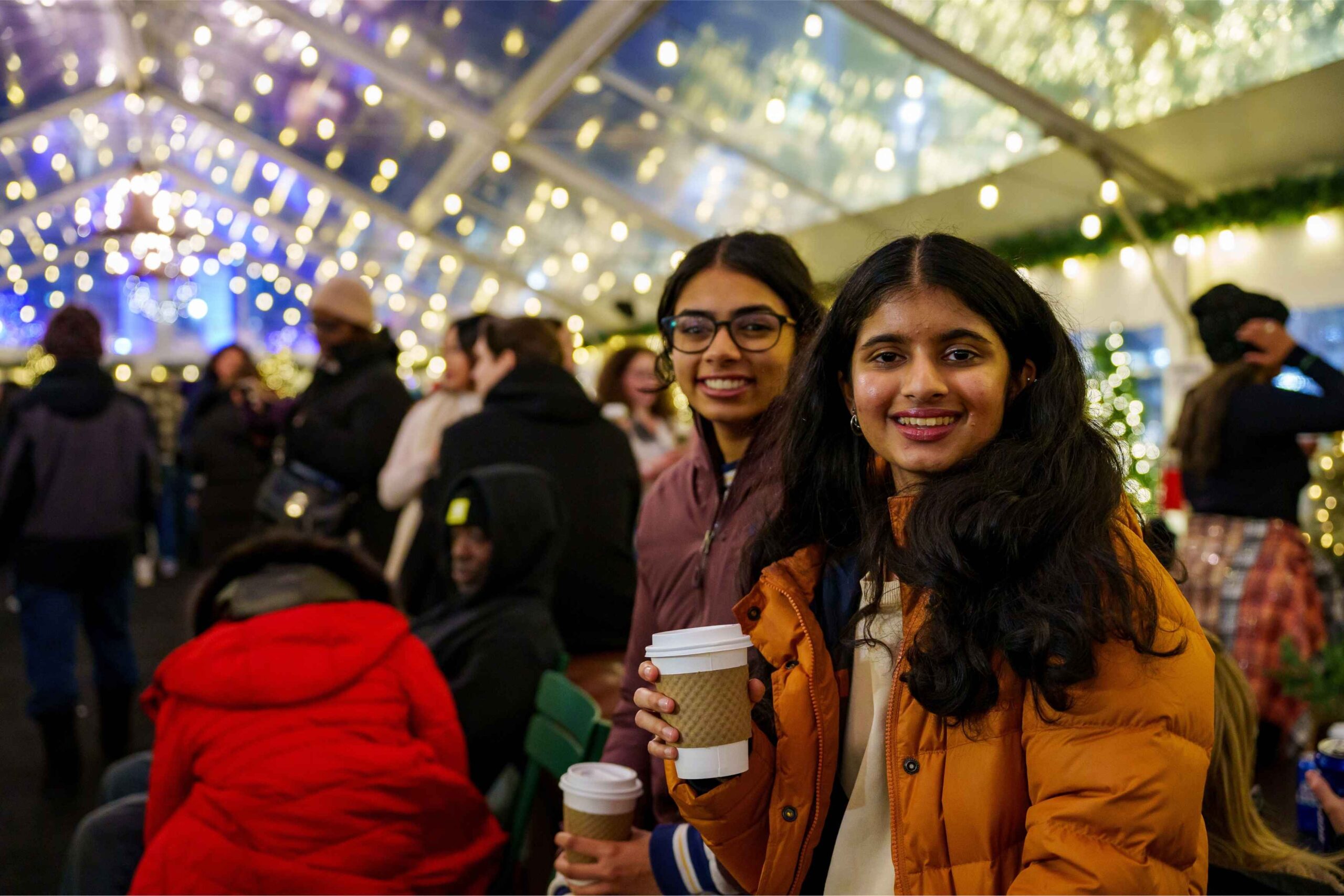 Visitors enjoy hot drinks under twinkling lights during the Downtown Detroit Tree Lighting at Campus Martius Park, a festive holiday event.