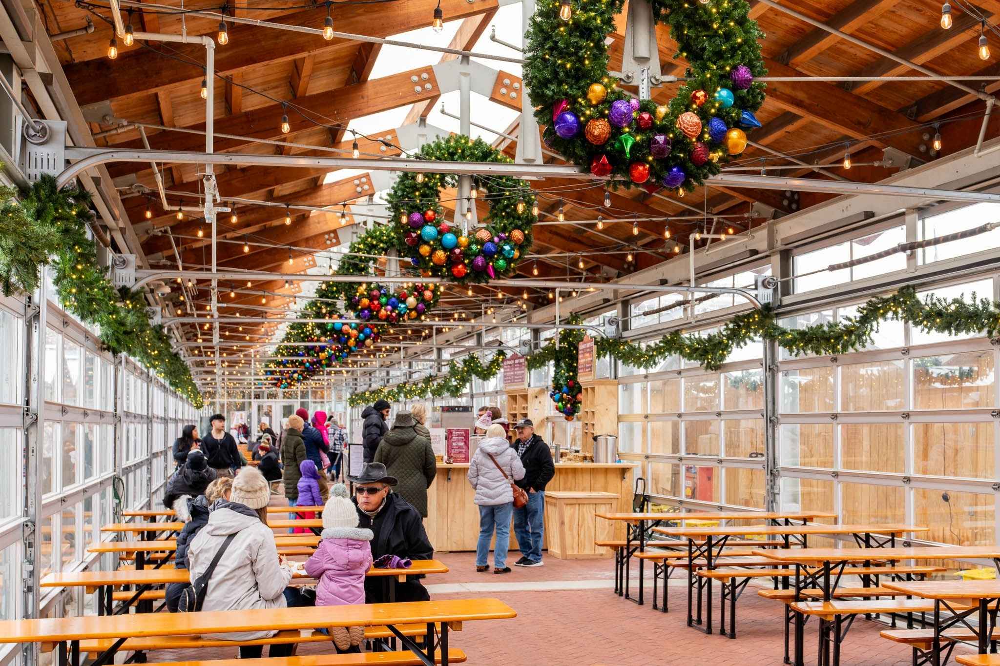 Families gather inside the Christkindl Markt beverage hall in Grand Rapids, enjoying holiday wreaths lights and warm treats during the Christmas season.
