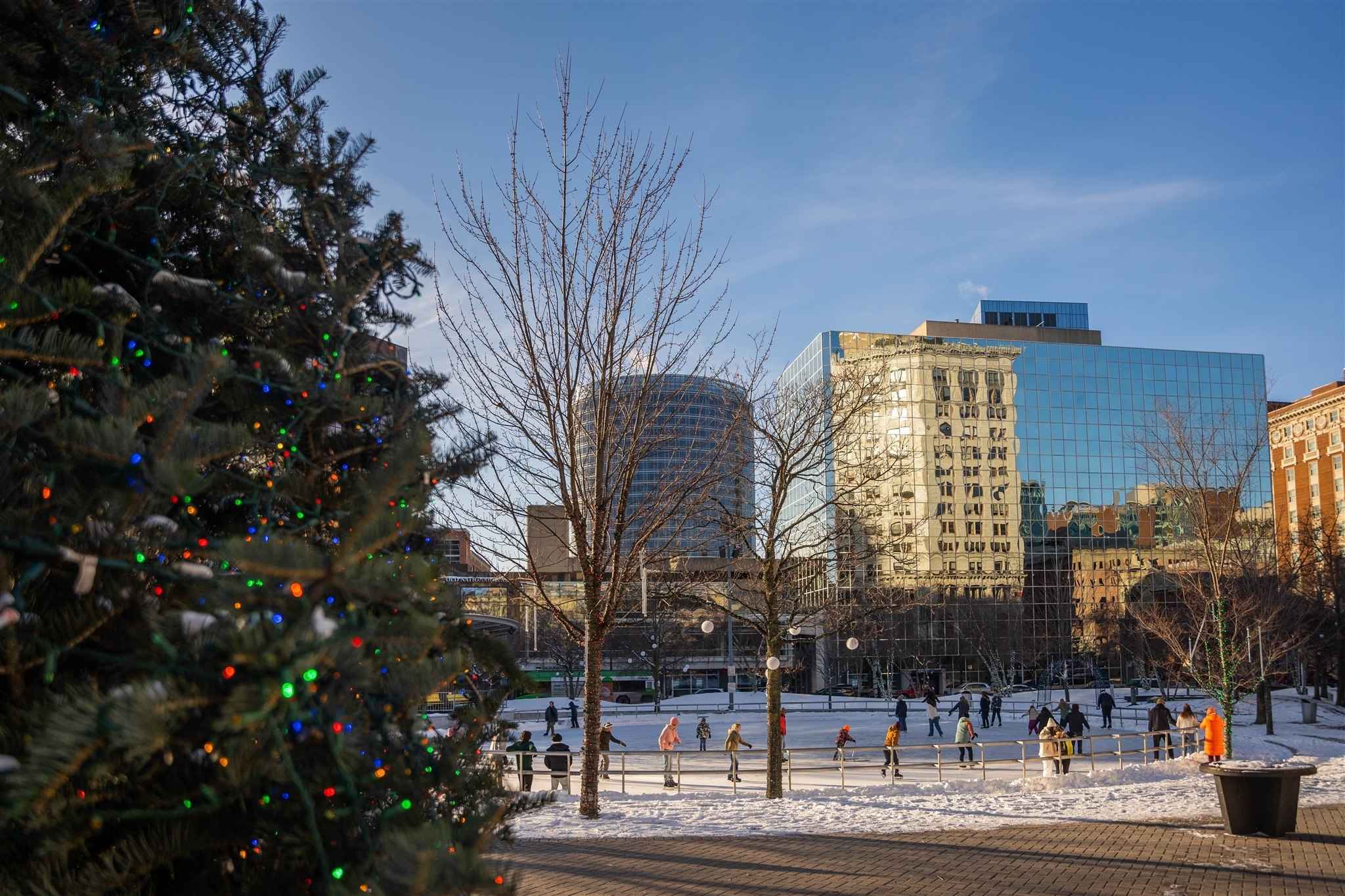 Families skate at Rosa Parks Circle in downtown Grand Rapids with holiday lights and snowy winter scenery during the Christmas season.