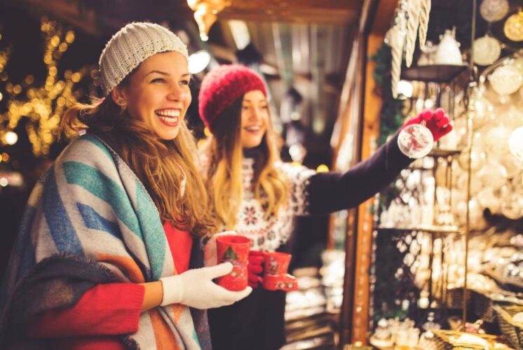 Two women shop for ornaments at a festive holiday market, capturing the spirit of the Grateful Gathering Holiday Market at Russell Industrial Center
