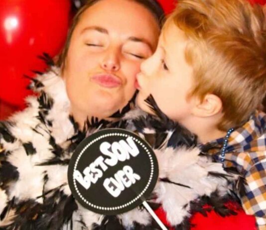 Mom and son share a fun photo moment at the High Tops and High Heels Dance at Glen Oaks Golf Course surrounded by red balloons.