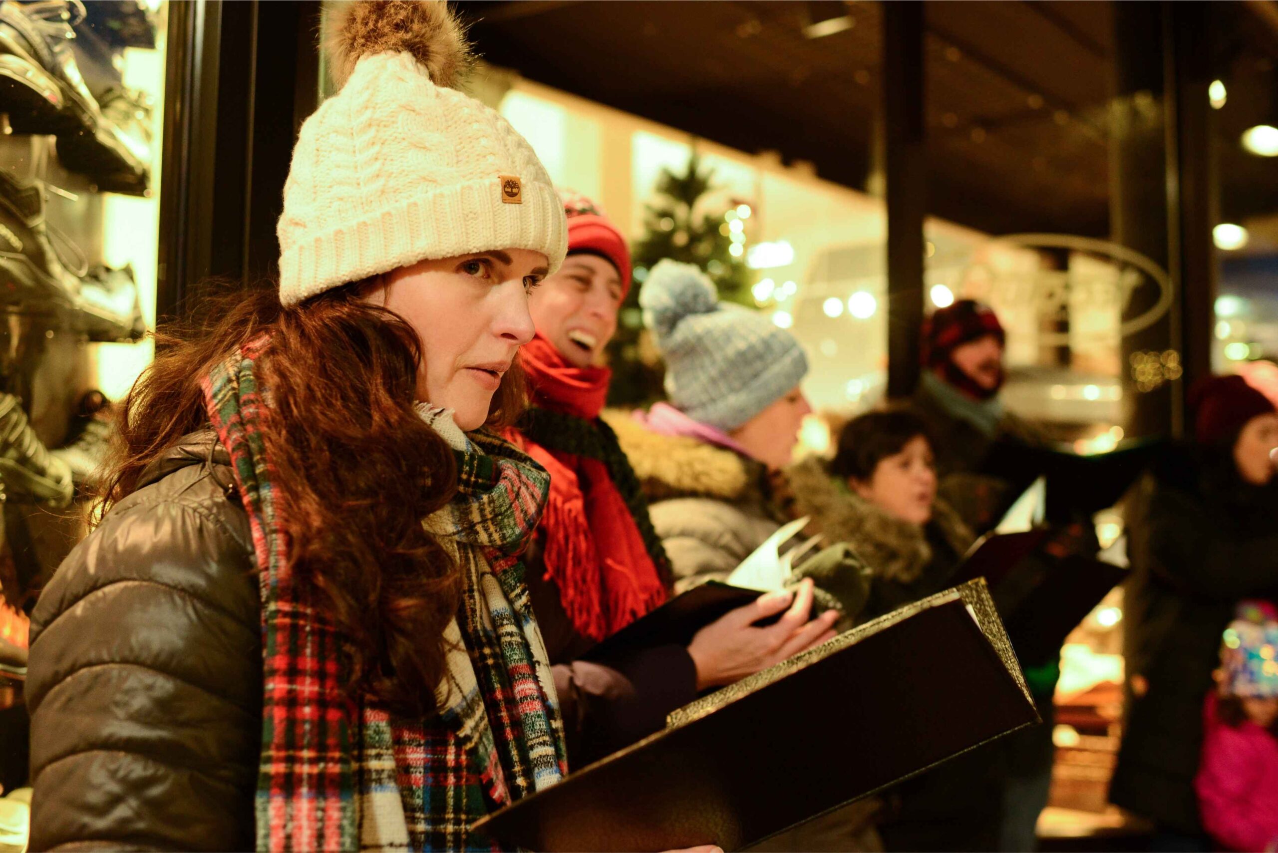 Carolers bundled in winter hats and scarves sing in downtown Holland during a festive Holland Michigan Christmas celebration.
